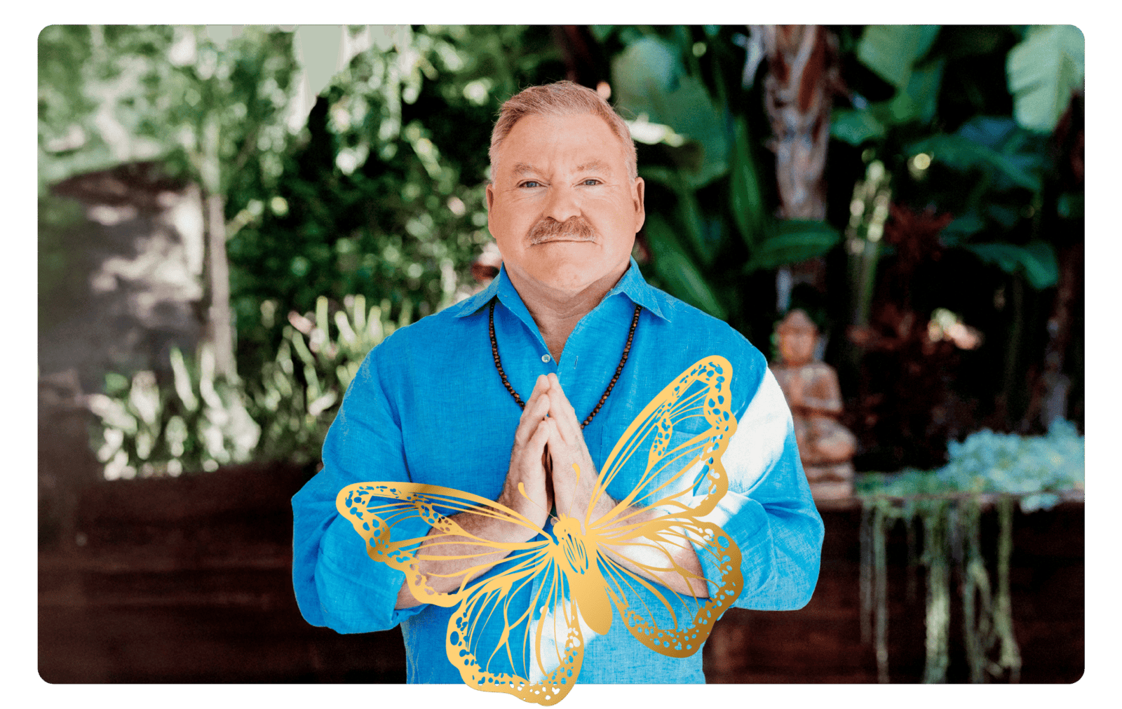 A man in a blue shirt stands outdoors with palms pressed together, overlaid with a golden butterfly graphic, and greenery in the background.